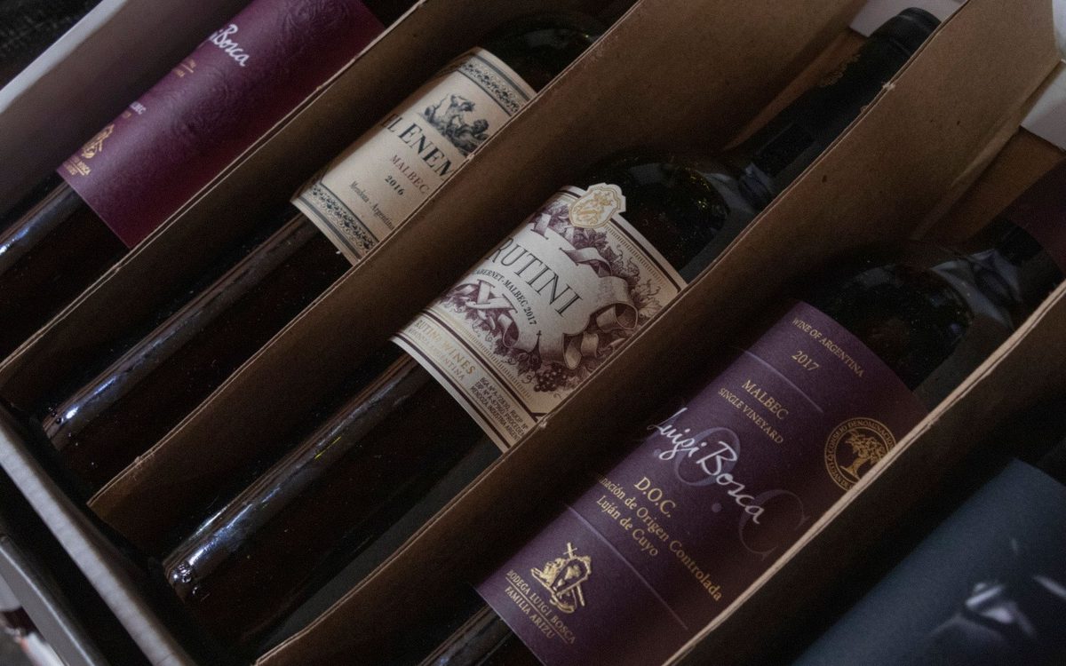 Red wine bottles with labels packed in a box, ready for storage in a wine fridge.