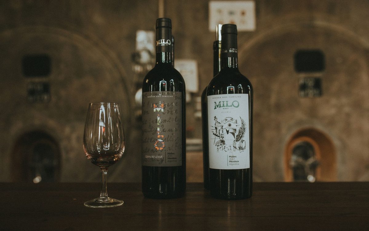 Two wine bottles with a glass in a rustic setting, ideal for showing wine storage temperature.